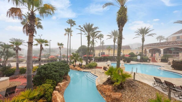 A resort with a swimming pool, palm trees, and lounge chairs. - Cozy Stylish Townhome (Davenport)