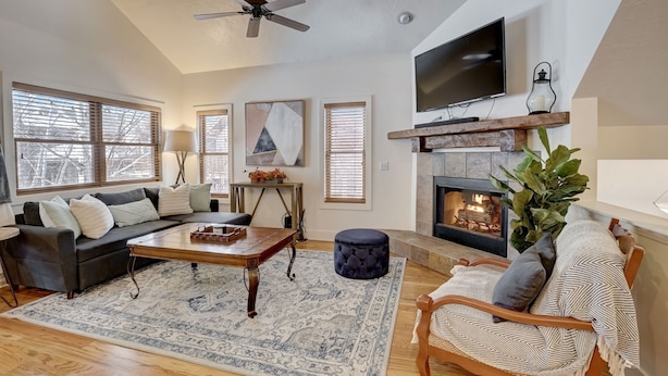 Una sala de estar acogedora con chimenea, un sofá, una mesa de centro y un televisor montado en la pared.