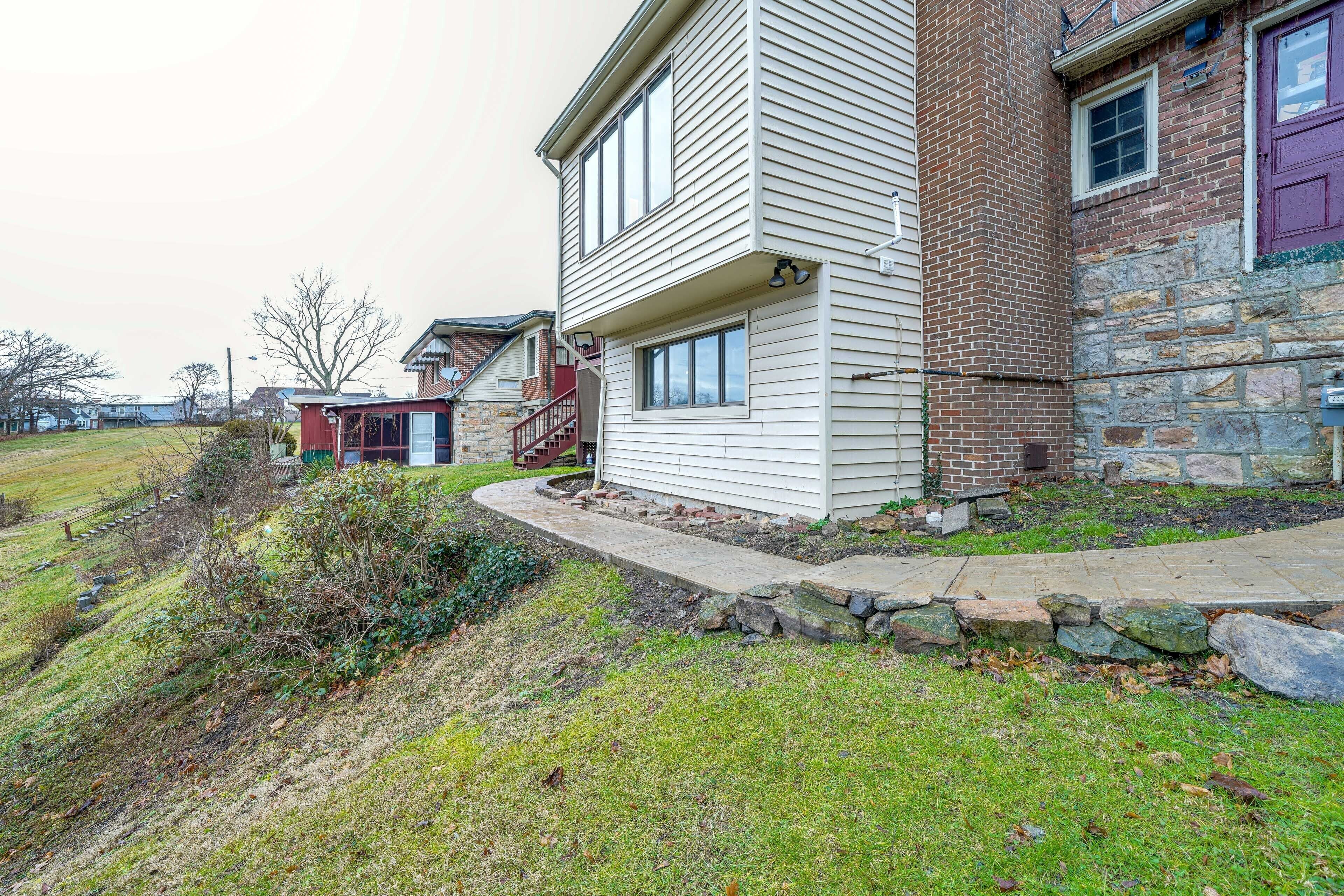 A residential property with a two-story house, a stone foundation, and a front yard with a pathway.