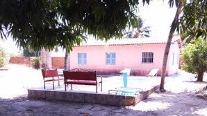 A sandy outdoor area with a bench and a pool. - Recanto Silvia Timbó (Tapera)