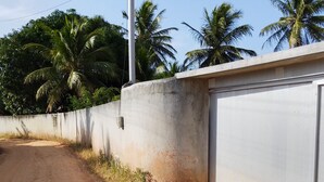 A dirt road leading to a concrete building with a garage door. - Recanto Silvia Timbó (Tapera)