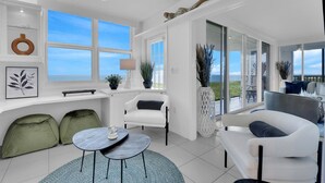 A modern living room with a view of the sea, white furniture, and a large window. - Enjoy this beautiful condo at St. Maarten in gorgeous, coastal Pelican Bay! (Naples)