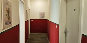 Un corridoio con pareti rosse e pavimento in legno, che conduce a una porta contrassegnata dal numero 3.