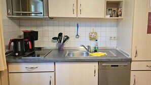 Eine moderne Küche mit Kaffeemaschine, Geschirr und einer Spülmittel-Zapfsäule.