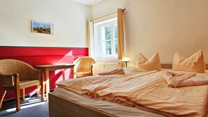 Una habitación de hotel con una cama, una silla, una mesa y una ventana.