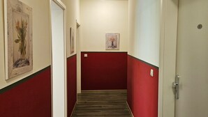 Un pasillo con paredes rojas y piso de madera, que conduce a una puerta con el número 3.