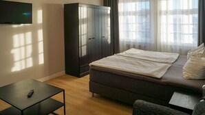 A modern hotel room with a bed, a wardrobe, a TV, and a small table. - Mollibahnhof West - Ferienwohnung 01 - Mollibahnhof - Kühlungsborn West (Kühlungsborn)