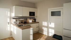 A compact kitchen with white cabinets, a microwave, a coffee maker, and a sink. - Mollibahnhof West - Ferienwohnung 01 - Mollibahnhof - Kühlungsborn West (Kühlungsborn)