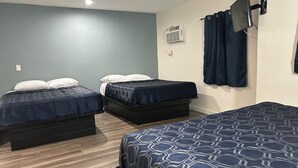 A room with two single beds, a TV mounted on the wall, and a ceiling fan. - Budget Inn Hollywood (Los Angeles)