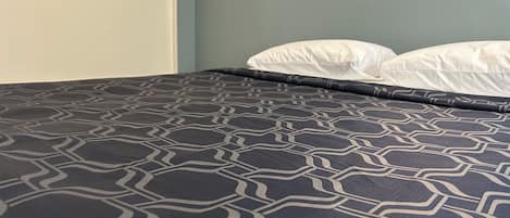 Un lit avec une couvre-lit à motifs et deux oreillers.