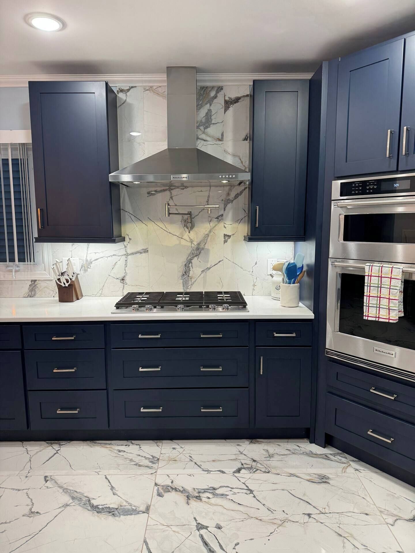 Una cocina moderna con armarios azul oscuro, una campana extractora de acero inoxidable y un horno empotrado.
