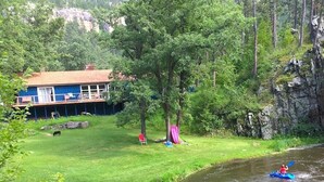 Une propriété située au bord de la rivière, comprenant une maison, une pelouse et une tente.