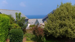 Un área residencial costera con casas de techos inclinados, rodeada de abundante vegetación y vista al mar.