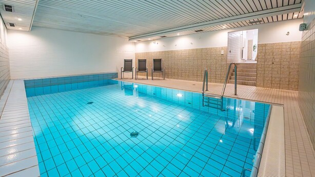 Ein großes Hallenbad mit Kachelwänden und einer Decke mit horizontalen Linien.