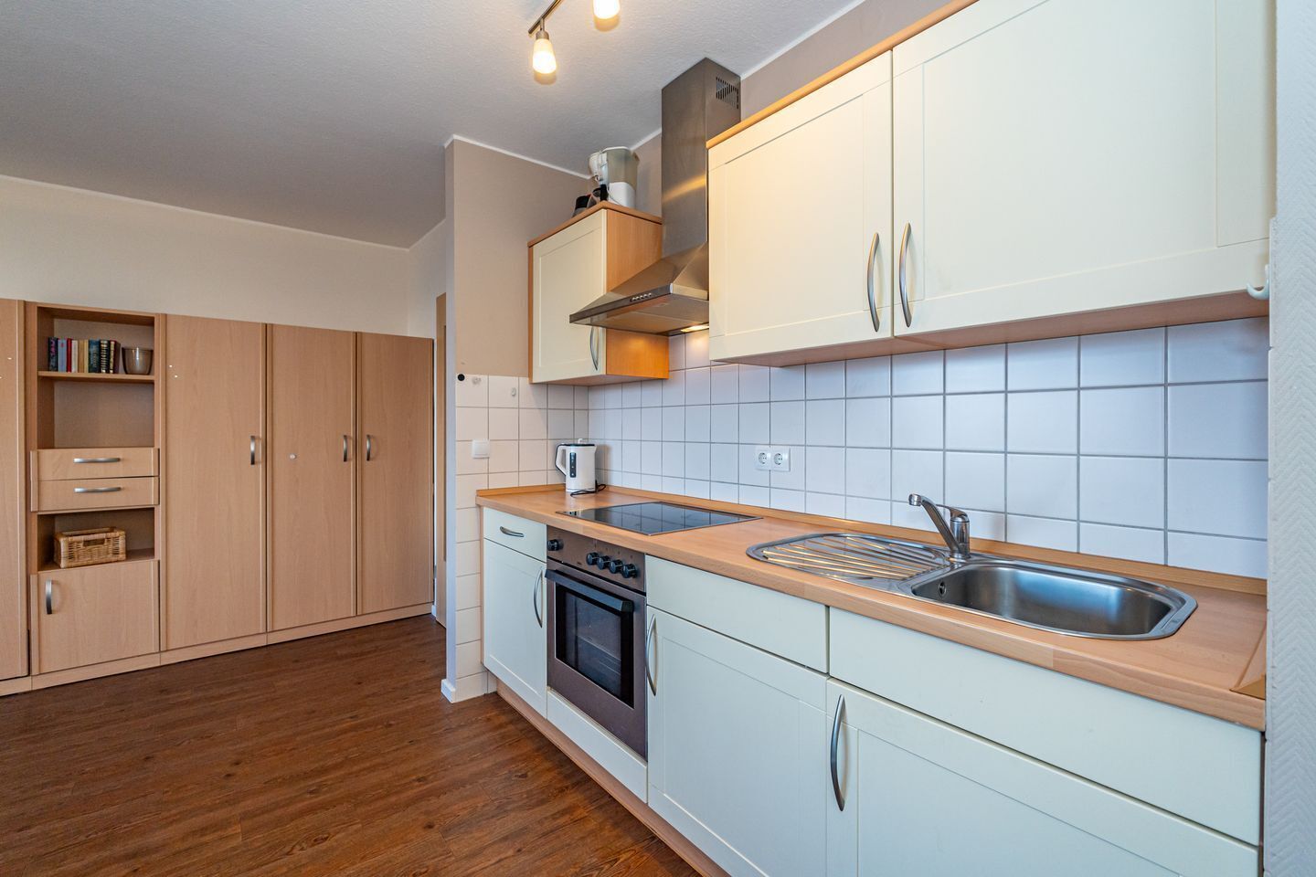 A modern kitchen with wooden cabinets, a stainless steel sink, and a built-in oven.