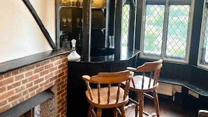 A cozy room with a brick fireplace, wooden chairs, and a window with a view of greenery.