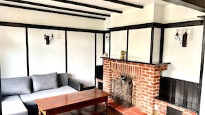 A cozy living room with a sectional sofa, a wooden coffee table, a brick fireplace, and black and white walls.