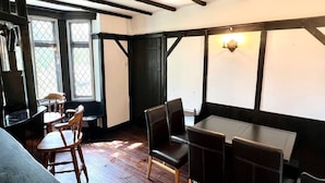 A room with wooden floors, a table with chairs, and a window with a view.