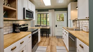 A modern kitchen with white cabinets, a microwave, a coffee maker, and a dishwasher. - Cozy retreat, newly renovated with loft, hot tub, creek access, pet friendly (Rhododendron)