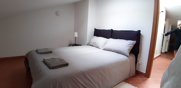 A bedroom with a bed, a nightstand, and a lamp.