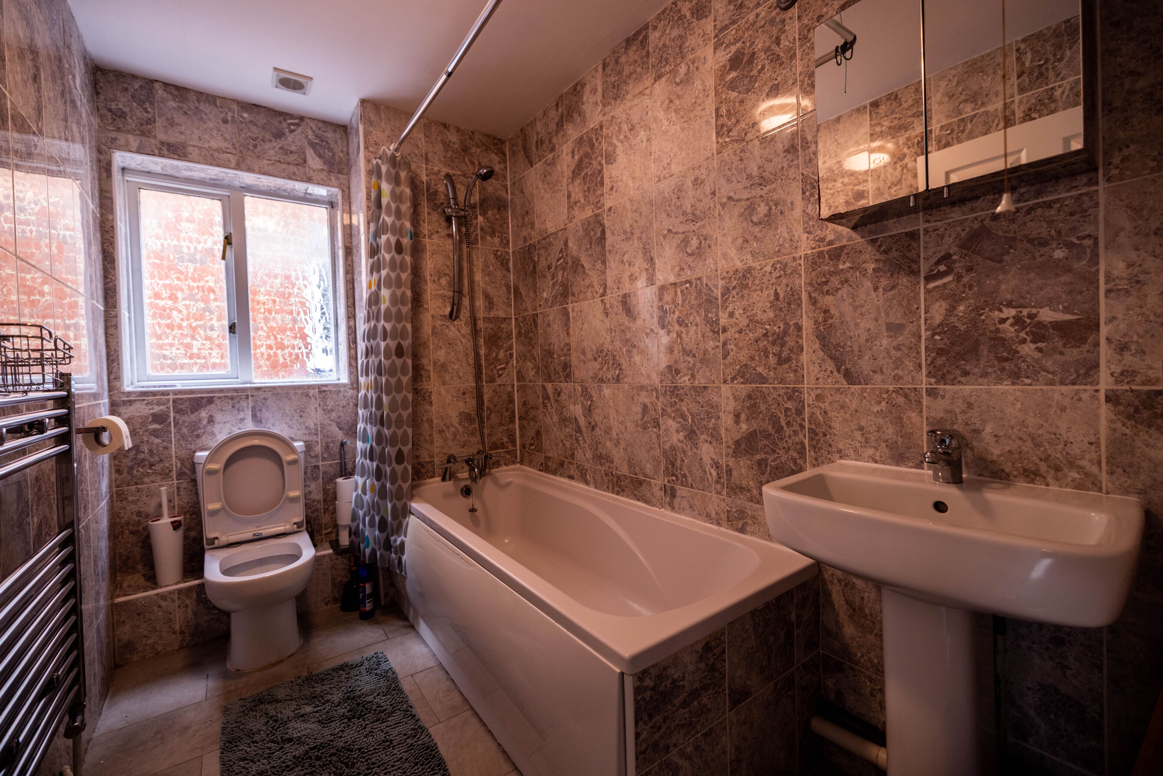 A bathroom with a bathtub, a sink, a toilet, and a window.