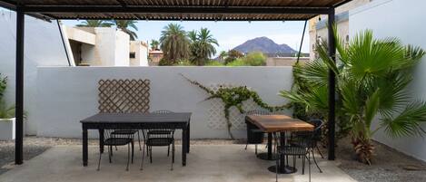 Une terrasse extérieure avec deux tables et des chaises, une pergola et une vue sur une montagne.
