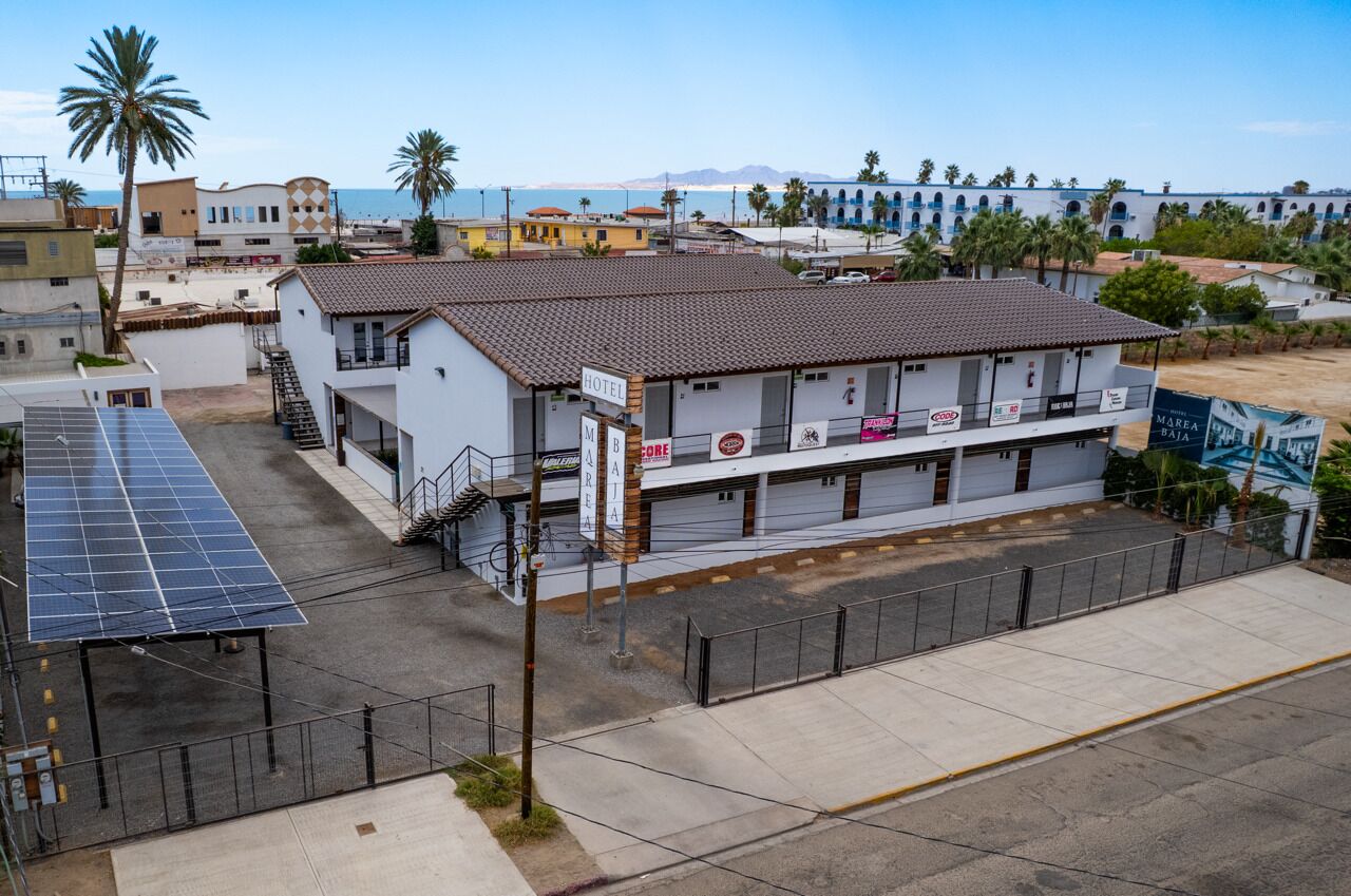 A two-story building with a sign indicating it is a hotel. There is a solar panel array on the left side.