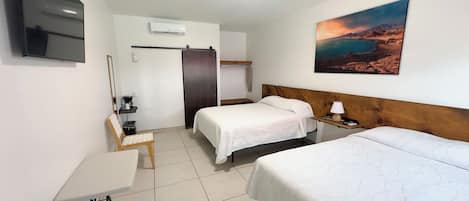 A hotel room with two beds, a desk, a TV, and a painting on the wall.