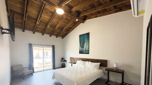 A bedroom with a bed, a nightstand, a lamp, a painting on the wall, and a window.