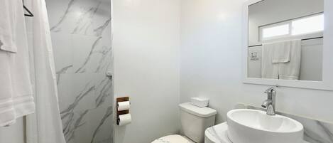A bathroom with a shower, toilet, and sink.