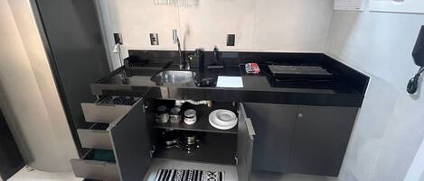 Una cuina compacta amb microones, batedora i cafetera damunt l'encimera.