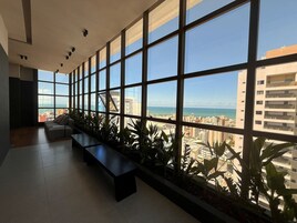 Un intérieur moderne avec de grandes fenêtres, un banc et des plantes en pot.