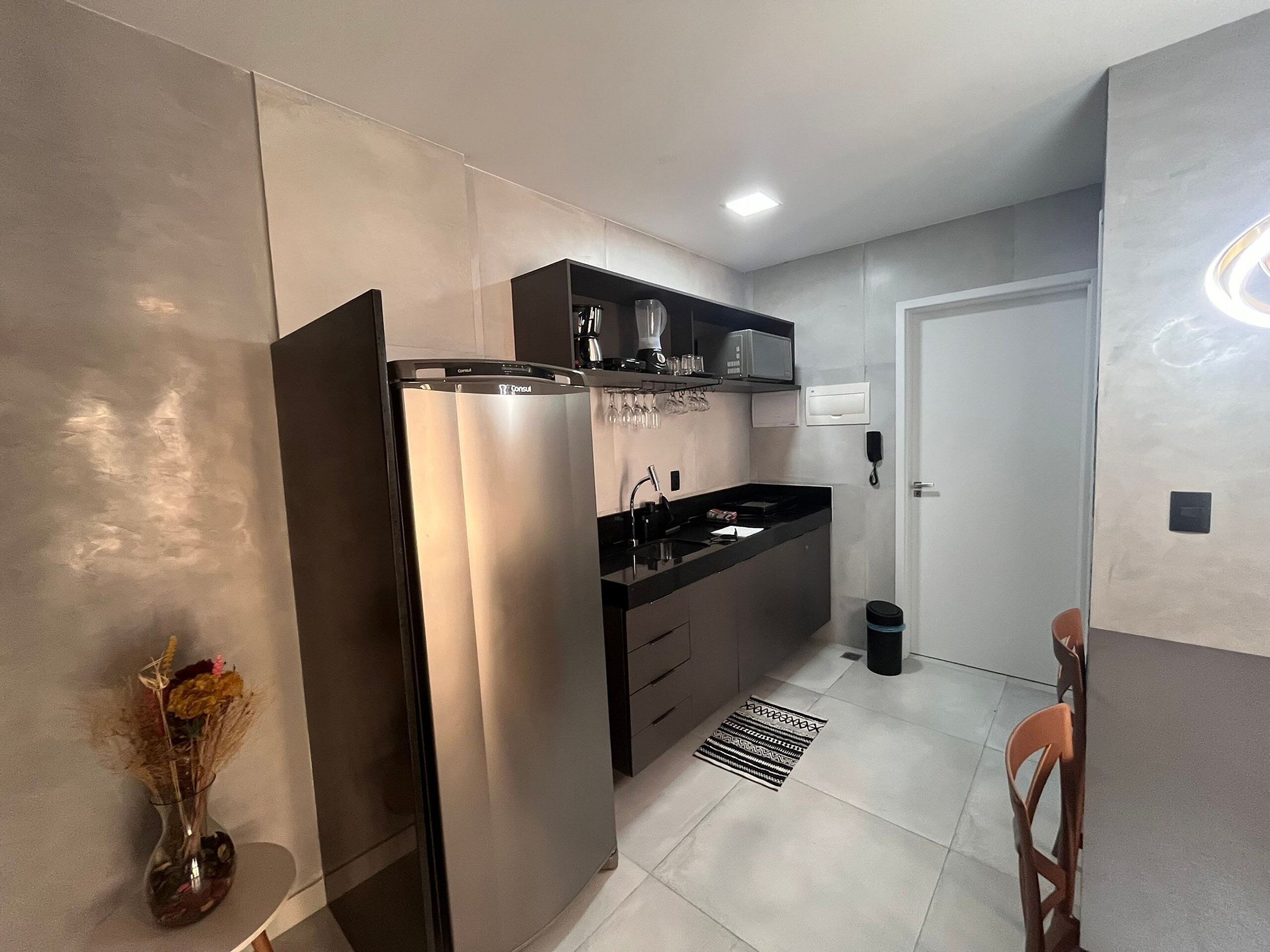 Eine moderne Küche mit Kühlschrank, Mikrowelle und einer schwarzen Arbeitsplatte.