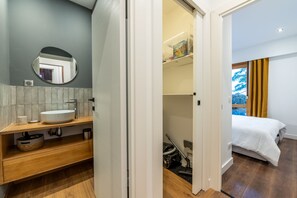 A modern bathroom with a round mirror, wooden vanity, and a sink.
