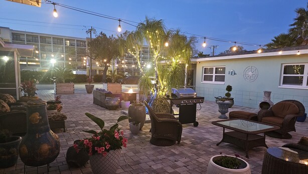Eine Außenpatio-Terrasse mit Sitzgelegenheiten, einem Grill und dekorativer Beleuchtung.