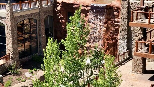 Un bâtiment à plusieurs niveaux doté d’une cascade, d’une architecture en pierre et d’espaces de détente en plein air.