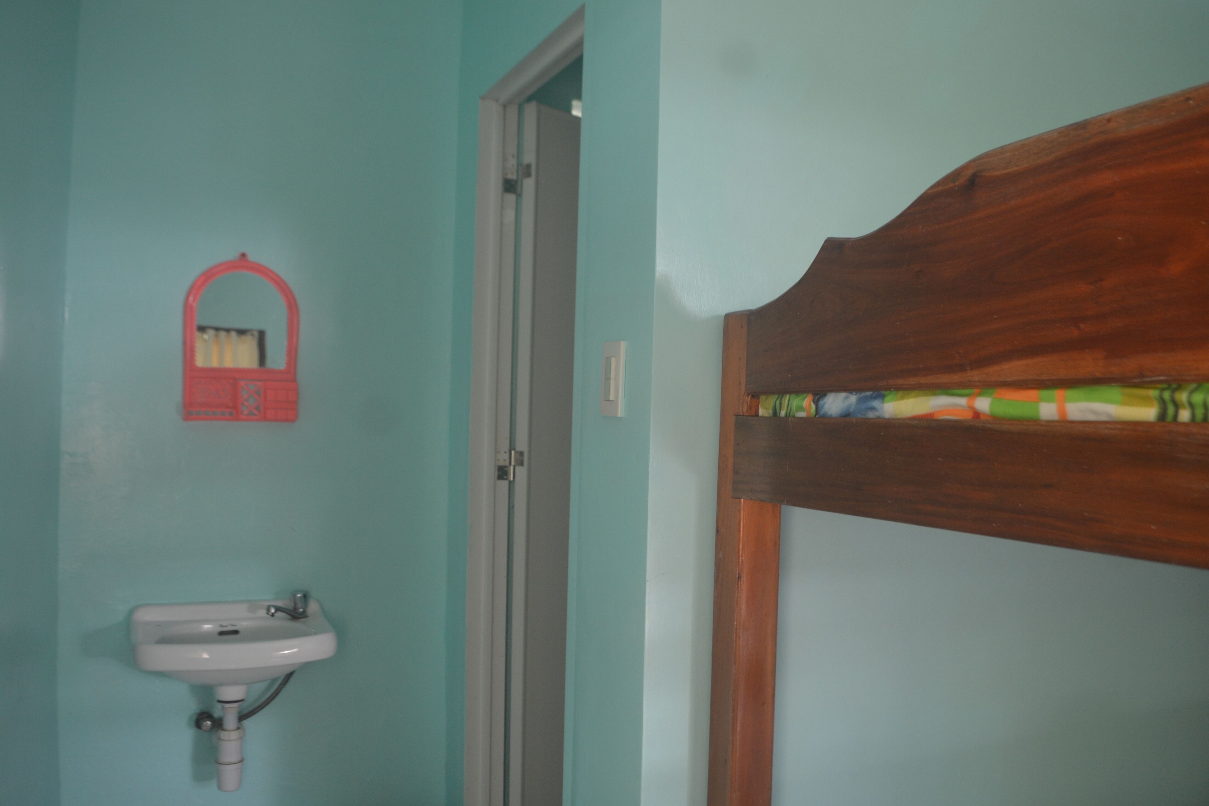 Une salle de bain avec une tête de lit en bois, un lavabo et un miroir.