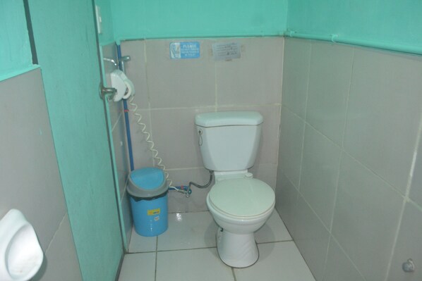 A small bathroom with a toilet, a blue trash bin, and a hand dryer.