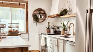 Una cocina moderna con armarios blancos, un refrigerador de acero inoxidable y una mesa de comedor de madera.