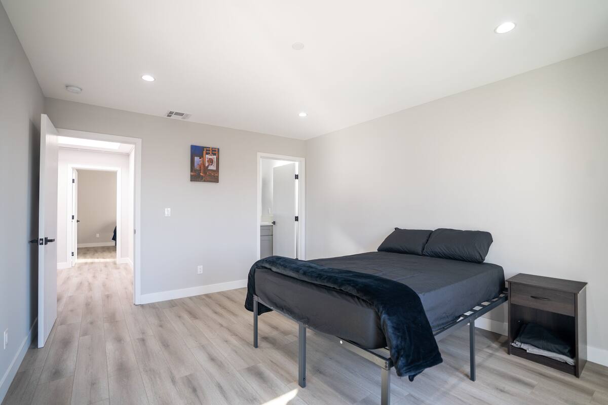 Une chambre à coucher comprenant un lit, une table de chevet et une porte donnant sur une autre pièce.