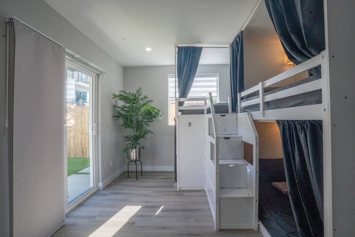 Une chambre avec un lit superposé, une plante en pot et une porte coulissante donnant sur un espace extérieur.