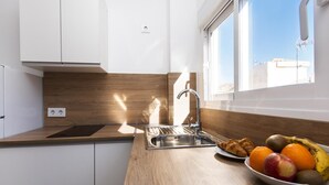 A modern kitchen with a wooden countertop, stainless steel sink, and a bowl of fruit. - Apartment Málaga tour Museums Constitucion Square (MALAGA)