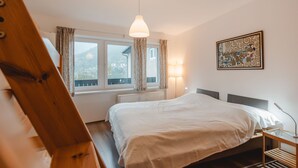 Een slaapkamer met een bed, een raam met gordijnen, een bedlampje en een wanddecoratie.