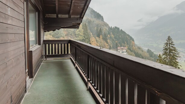 Ein hölzerner Balkon mit Blick auf eine gebirgige Landschaft.