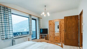 Ein Schlafzimmer mit einem Bett, einem Fernseher, einem Kleiderschrank und einem Fenster mit Vorhängen.