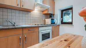 Eine moderne Küche mit Holzausstattung, einem eingebauten Backofen, einer Mikrowelle und einem Fenster mit Blick auf Grünflächen.