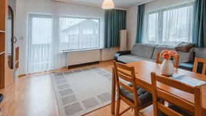 A modern living room with a sofa, dining table, chairs, and a radiator. - Landhaus St. Georg by Interhome (Bad Gastein)