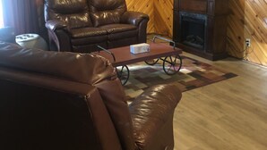 Una sala de estar con techo de madera inclinado, un sofá de cuero, un televisor y una chimenea.