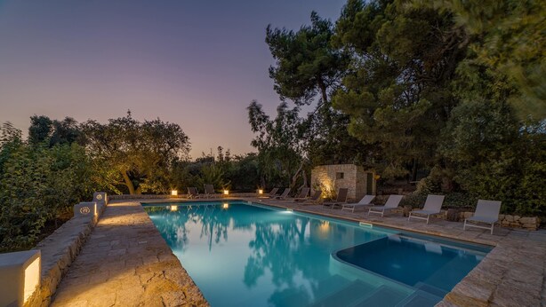 A rectangular pool with a stone border, surrounded by lounge chairs and a stone wall. - Villa Giari 8 Emma Villas (Ceglie Messapica)