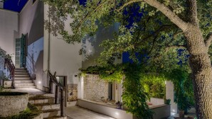 A modern building with a stone staircase, a wooden railing, and a tree with green foliage. - Villa Giari 8 Emma Villas (Ceglie Messapica)